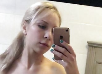 Blonde aux gros seins et fesses rondes en string rose fait un selfie devant son miroir